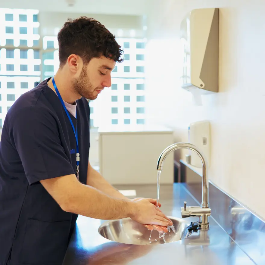 Un homme se lave les mains sous un robinet, en utilisant du savon.