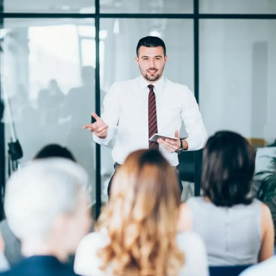 Un homme d'affaires présente à un groupe de personnes attentives dans une salle de réunion.