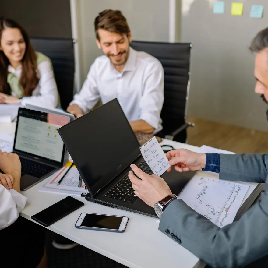 Des professionnels d'affaires collaborent autour d'une table, utilisant des ordinateurs portables.
