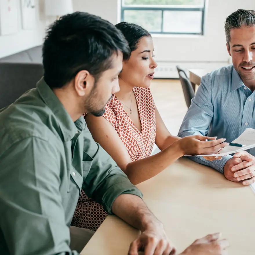 Trois personnes assises à une table, comprenant un homme et une femme, discutent ensemble.