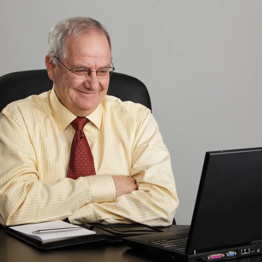 Un homme assis à un bureau, utilisant un ordinateur portable.