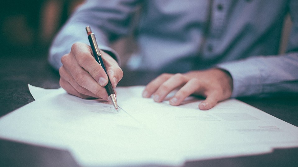Un homme signe un contrat avec un stylo, illustrant un moment d'engagement formel